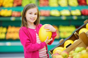Fototapeta na wymiar Little girl choosing a melon in a food store or a supermarket