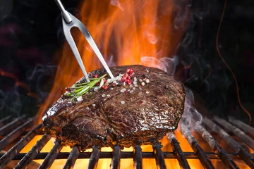 Tuinposter Grilled beef steak on the grill. © Lukas Gojda