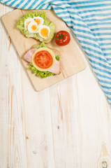 Healthy breakfast with hard boiled egg, bread, tomato and salad on white wooden table. Top view with copy space for text.