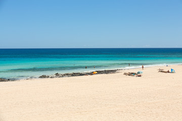 Fototapeta na wymiar Tourists rest on Corralejo Beach on Fuerteventura, Canary Islands