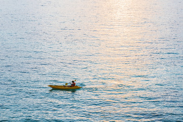 Fototapeta premium Kayak, a guy kayaking on blue ocean in sunset with sunlight reflection on the sea