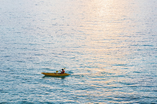 Kayak, A Guy Kayaking On Blue Ocean In Sunset With Sunlight Reflection On The Sea