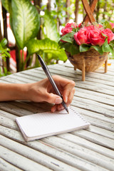 Female hand writing in a notebook on wooden table