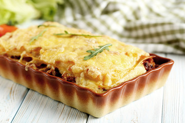 Italian lasagna in bowl on a blue wooden table