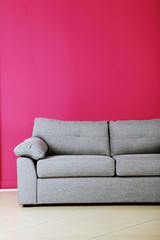 Grey sofa on a pink background, close up