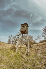 Retro toned fisheye lens photo of a hunting pulpit on a field, Poland.