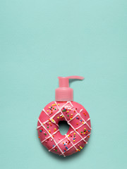 Donut pump / Creative still life of a tasty sweet donut with a cosmetic pump dispenser on blue background.