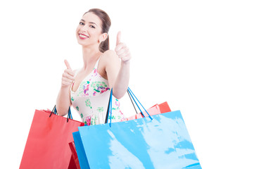 Pretty lady holding shopping bags making like approval gesture