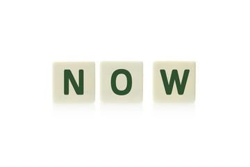 Word "Now" on board game square plastic tile pieces, isolated on a white background.