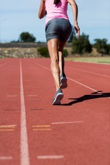 Obraz premium Rear view of female athlete running on the running track