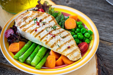 Grilled turkey fillet with vegetables on wooden background