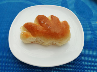 Sweet bun on white plate, which stands on a blue tablecloth