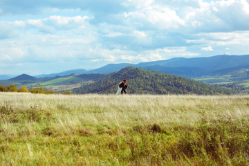 Obraz premium A view from afar on a wedding couple walking up on the hill amon
