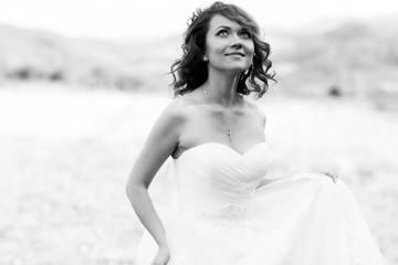 Fototapeta na wymiar A black and white photograph of a shiny bride standing on the hi