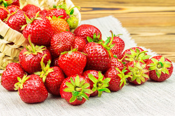 Full basket of strawberries that are poured out on canvas
