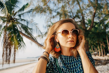 Young pretty girl on the beach with palms 