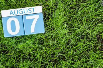 August 7th. Image of august 7 wooden color calendar on green grass lawn background. Summer day. Empty space for text