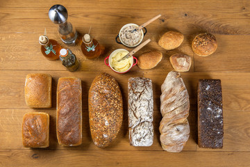 Widok z góry na aranżację chlebów i bułek oraz dodatki w postaci masła, smalcu i oliwy