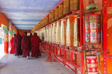 Buddhist nun walking touch a prayer wheels around the sanctuary at Larung gar (Buddhist Academy) in...