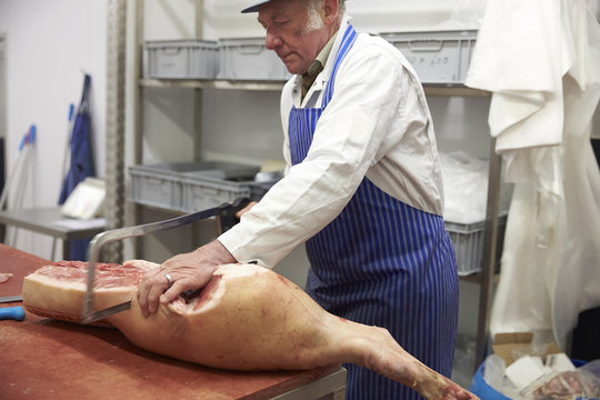 Butcher Preparing Joint Of Pork On Chopping Board