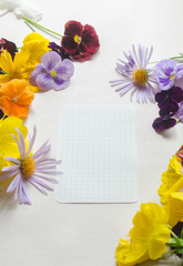 Colorful and beautiful flowers and a sheet of paper on the white background