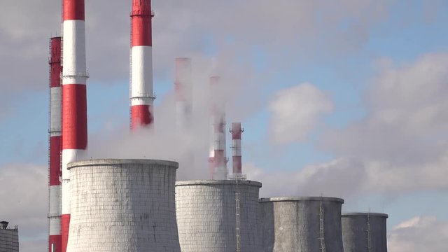 Smoke stacks and cooling towers against cloudy sky