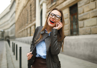 Fototapeta premium Businesswoman walking down the street while talking on smart pho