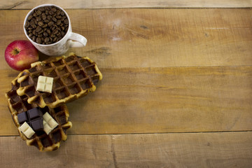 Top wiew of fresh waffles with apples, chocolate and cup full of
