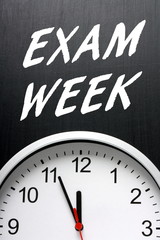 The words Exam Week on a blackboard above a modern wall clock as a reminder