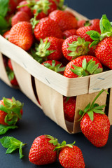Ripe strawberries in a wooden basket on black