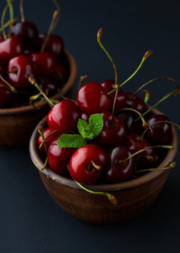 Ripe cherries in a clay bowl on black background