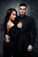 Elegant young woman in black dress with handsome man in a black suit