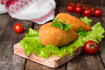 Chicken cutlets in breadcrumbs - Chicken Kiev on wood board and wooden background. Ukrainian cuisine. Selective focus