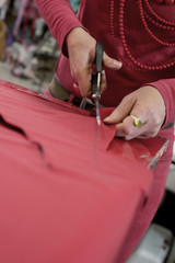 Obraz na płótnie Canvas A Pair of Scissors Cutting Through Red Cloth