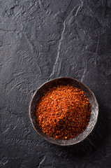 Long black pepper in metal bowl on dark stone background. Selective focus. Top view. Background with place for text
