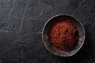 sumah or sumak - east spice in metal bowl on dark background. Selective focus. Top view.Background with place for some text