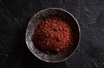 sumah or sumak - east spice in metal bowl on dark background. Selective focus. Top view.Background with place for some text