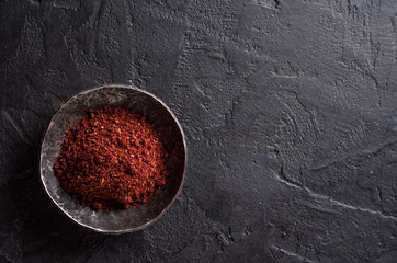 sumah or sumak - east spice in metal bowl on dark background. Selective focus. Top view.Background with place for some text