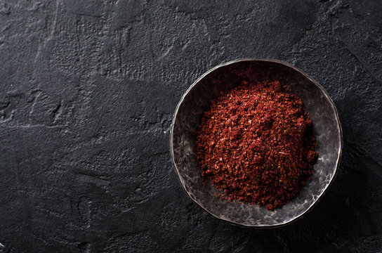 sumah or sumak - east spice in metal bowl on dark background. Selective focus. Top view.Background with place for some text