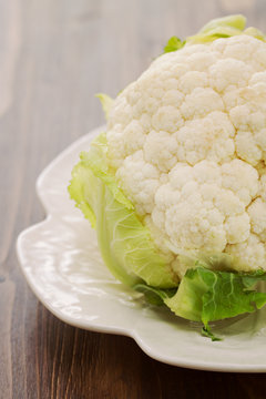 cauliflower on white dish on brown wooden background