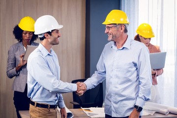 Two architects shaking hands in office