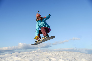 Young woman on the snowboard jumping