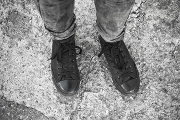 Feet in black gumshoes and gray jeans