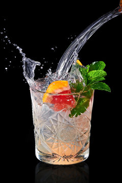 Splash of refreshing lemonade in faceted glass decorated with a slice of grapefruit