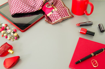 Women modern desktop with red accessories: tablet, dairy, cosmetic, pen, cup of coffee.Copyspace.