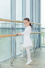 Little ballerina girl. Adorable child dancing classical ballet in a white studio.