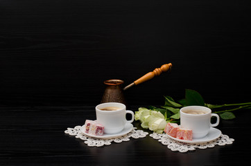 A couple cups of coffee with milk, Cezve, Turkish Delight, a bouquet of white roses on a black background. Space for text