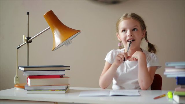 Girl learning lessons, cute girl making her homework, schoolgirl studing at home at the table