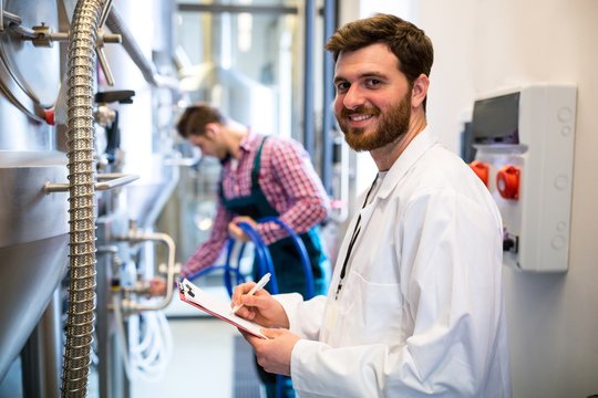 Maintenance workers examining brewery machine