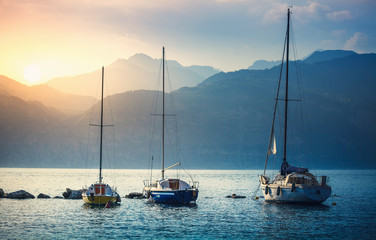 Sailers boats sailing by sea waves in evening sunset